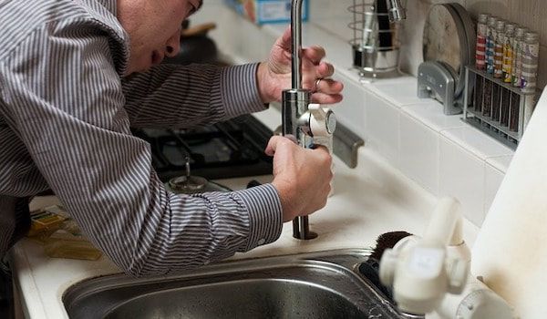 Plumber fitting pipework beneath a sink