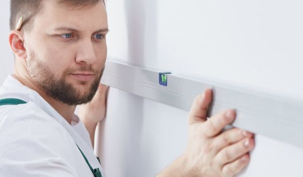 Decorator checking a spirit level against a wall